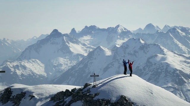 登山者在白雪覆盖的山顶上兴高采烈视频下载