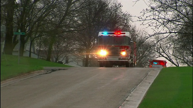 中远镜头泛左-闪灯的消防车在街道上疾驰。视频下载