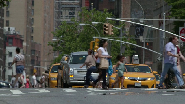 一排出租汽车沿着第七大道驶往布里克街。一群游客过马路。视频素材