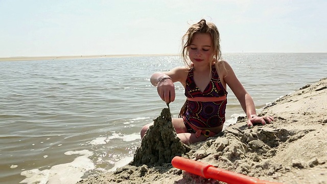 小女孩在沙滩上玩沙子/圣西蒙岛，美国乔治亚州视频素材