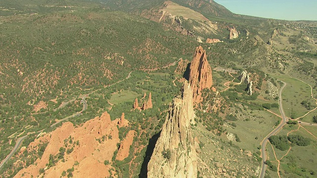 WS DS鸟瞰图的大红色岩石岩层突出到地面空气在日光与绿树周围/科罗拉多斯普林斯，科罗拉多州，美国视频素材