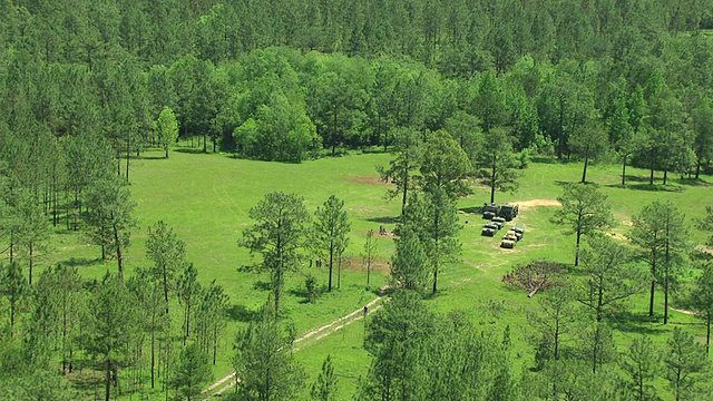 在美国密西西比州的谢尔比军营，士兵们在草地上工作，从草地上拉出来，露出WS开阔的田野和森林视频素材