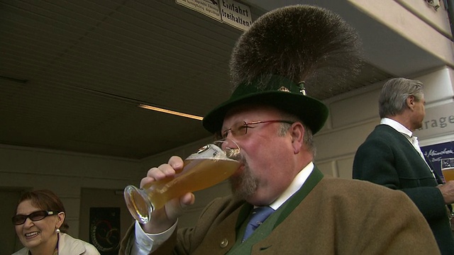 穿着戏服的传统巴伐利亚男人喝啤酒视频素材