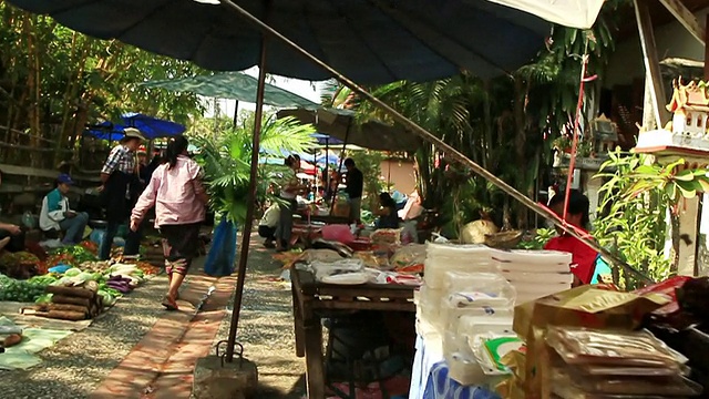 MS POV SLO MO在老挝琅勃拉邦的街道上，人们带着遮阳伞和产品行走在街道两旁视频素材