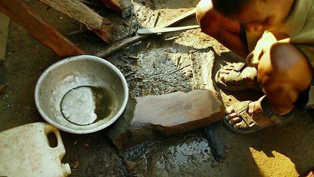 MS SLO MO男子在石板上磨砍刀的镜头/琅勃拉邦，老挝视频下载