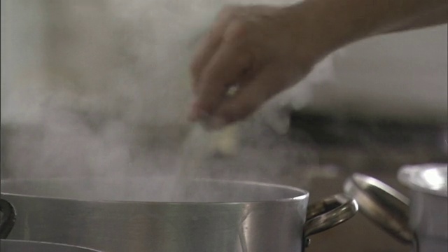 一个厨师用叉子把意大利面放进平底锅里，然后把意大利面扔出去。/西西里、意大利视频下载
