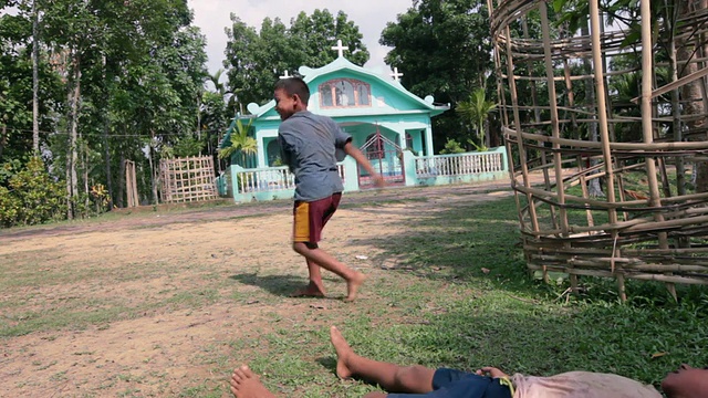 一群来自卡西战争部落、加罗部落的孩子在当地天主教教堂前玩耍，尼拉拉帕拉(村庄)，斯里曼加尔(Srimangal)，孟加拉，印度，亚洲视频下载