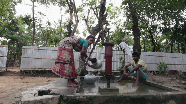 在离斯瑞曼加尔不远的一个村子里，一名妇女正在往桶里抽水视频下载