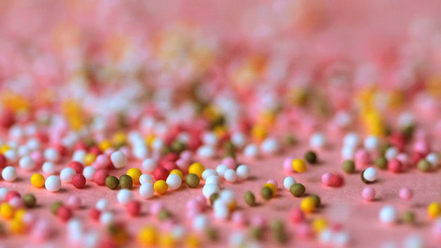 Sprinkles falling on pink surface视频素材