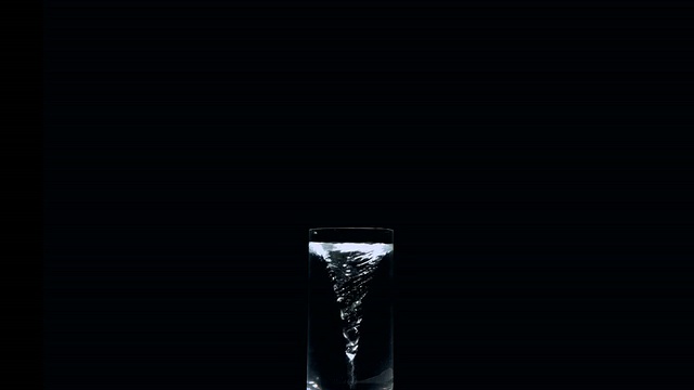 漩涡在一杯水上的黑色背景视频素材