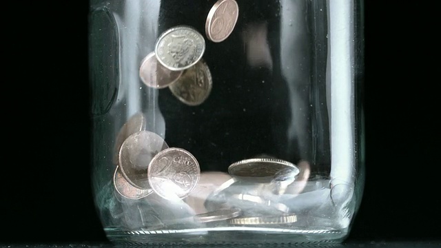 许多硬币倒入玻璃罐中闭合视频素材