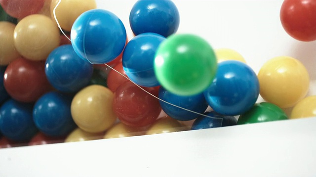 CU TD SLO MO彩色塑胶球从破碎的货柜/英国落下视频素材