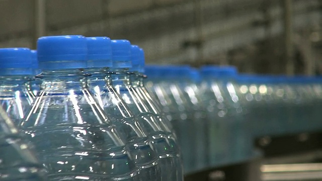 在德国莱茵兰-普法尔茨的饮料工业装瓶厂中移动的塑料瓶的CU镜头视频下载