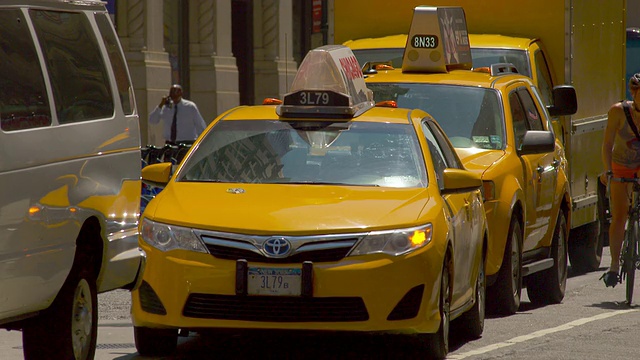 当车辆经过时，一辆开着转向灯的出租车等待转弯。视频素材