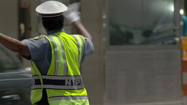 在纽约市一个炎热的夏天，一名NYDP警察指挥交通。视频下载