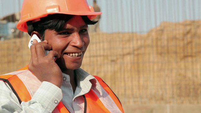 印度德里，一名建筑工人微笑着用手机交谈视频素材