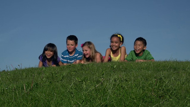 一群孩子躺在绿色的草山上视频下载