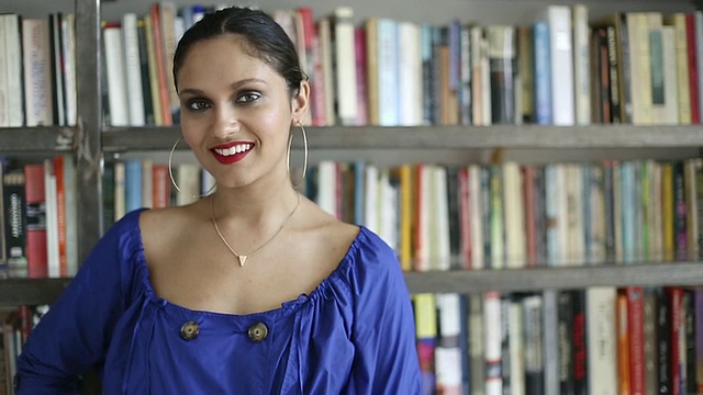 一个年轻漂亮的印度女人站在书架前视频素材
