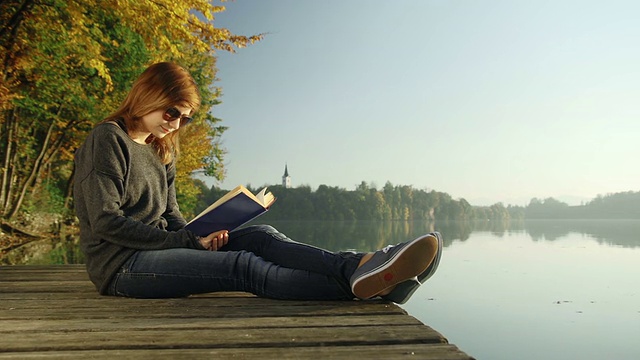 年轻女子在湖边看书视频素材