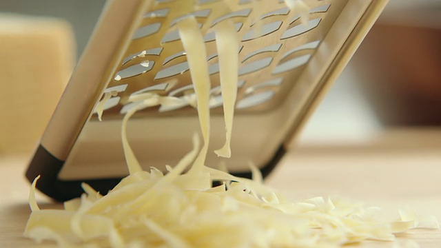 ECU视图在粗规奶酪刨丝器下面，奶酪从上面被磨碎并落在前景堆中。/美国加州的洛杉矶视频下载
