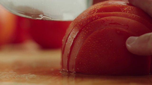 CU半块有机番茄放在厨房砧板上，用钢刀切成薄片/美国加州洛杉矶视频素材