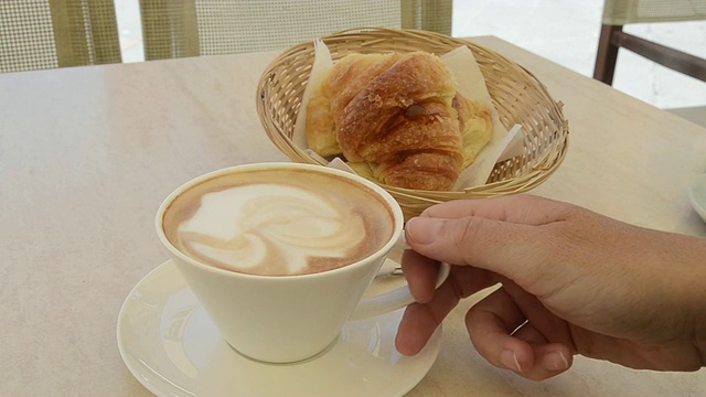 一名女子用勺子搅拌卡布奇诺咖啡，拿着咖啡杯喝/意大利托斯卡纳，彼得拉桑塔视频素材