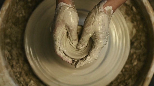 拍摄于日本京都陶艺城，一名女性陶工在陶艺轮上用黏土块塑造陶罐视频素材