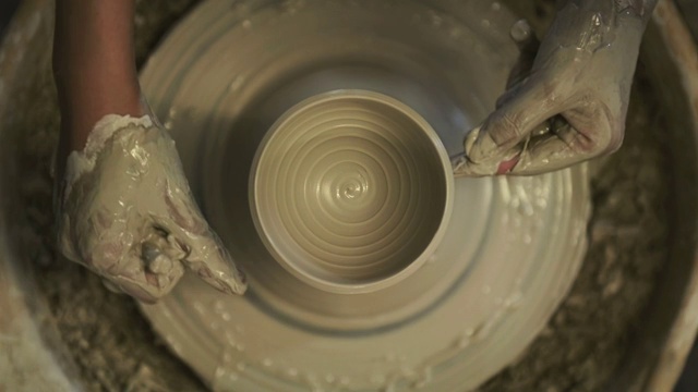 拍摄于日本京都陶艺城，一名女性陶工在陶艺轮上用黏土块塑造陶罐视频下载