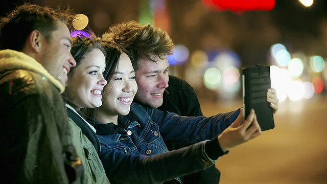 年轻人晚上在大城市玩平板电脑视频素材