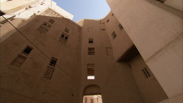 一条穿过公寓楼的拱门通向更多的泥砖高层建筑。视频下载
