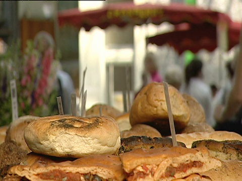 一个街头小贩在露天市场上成堆的面包。视频素材