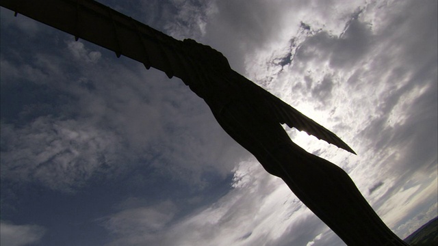 暴风雨的天空勾勒出盖茨黑德的北方天使雕像的轮廓。高清。视频下载