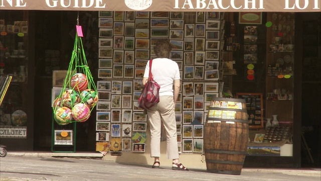 在意大利蒙特普尔西亚诺的一家商店里，一位橱窗购物者正在欣赏明信片。高清。视频素材