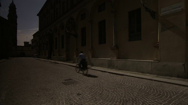一名骑自行车的人正沿着帕尔马大教堂前的石道骑行。高清。视频素材