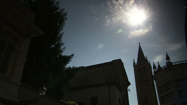 意大利帕尔马大教堂和洗礼堂的剪影上方悬挂着白炽的太阳。高清。视频下载