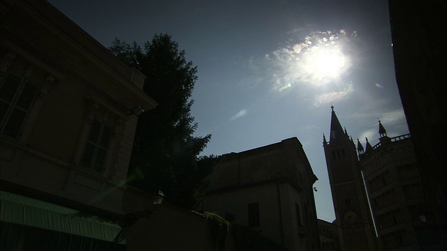 意大利帕尔马大教堂和洗礼堂的剪影上方悬挂着白炽的太阳。高清。视频下载