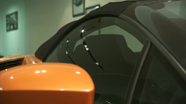 一辆豪华轿车的彩色车窗反射着经销商展厅里的灯光。视频素材