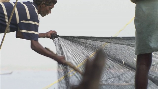 一个渔夫放了一张网，把鱼交给另一个渔夫。视频下载