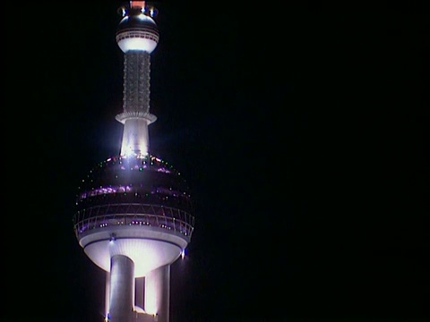 东方明珠塔顶部在夜空下闪耀，并反射着上海的天空视频下载