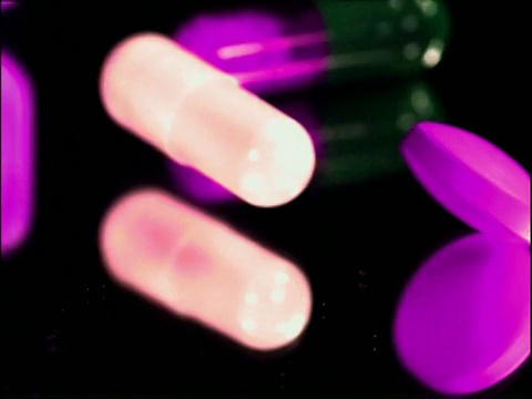 多种颜色的药片和胶囊落在反光表面视频下载