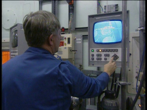 在塞拉菲尔德工厂，显示放射性废料容器的蓝屏监视器缩小到人观看监视器并按下按钮视频素材