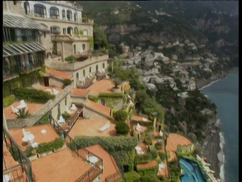 向右倾斜，俯瞰酒店的露台和建在悬崖上的游泳池，俯瞰下方的地中海和海滩视频下载