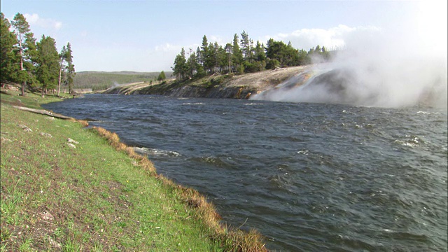 间歇泉中的水流入河流，导致蒸汽上升。高清。视频下载