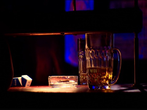 在迪斯科舞厅的闪光灯下，用手在啤酒杯旁的烟灰缸里掐灭香烟视频下载