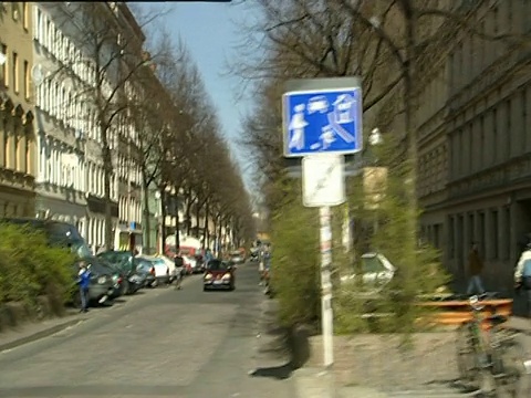 从汽车行驶穿过涂鸦充斥的居民区，包括街道边的咖啡馆、商店和骑自行车的东柏林视频素材