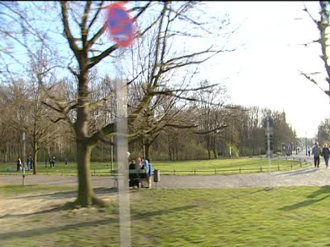 从汽车驾驶穿过公园区域，路过骑自行车的人和放松在草地上享受野餐和烧烤的人的轨道东柏林视频素材