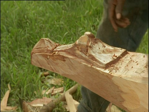 巴布亚新几内亚，一名男子将鳄鱼头雕刻在独木舟的船头上视频下载
