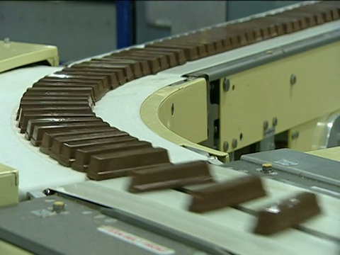 在工厂里，巧克力棒沿着传送带弯曲传递视频下载
