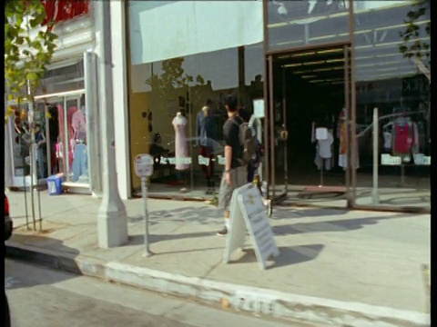 沿着洛杉矶的街道，左边的轨迹经过了行人和商店视频素材