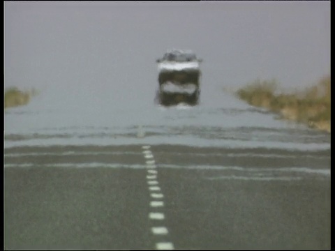 在纳米比亚，一辆白色的汽车穿过热雾(海市蜃楼效应)行驶在公路上视频素材